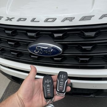 hand holding a key in front of a ford car