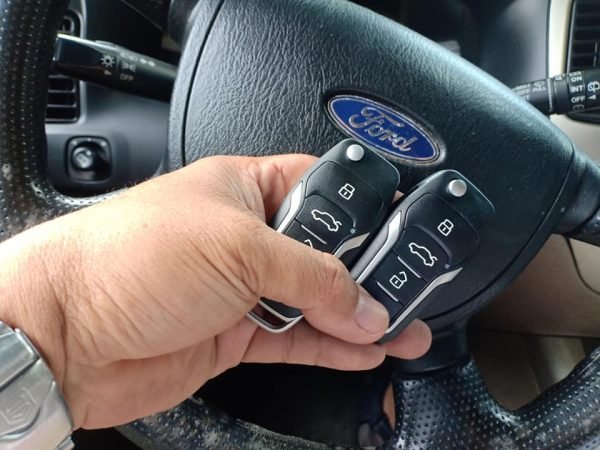 hand of a locksmith holding a two key inside a ford car