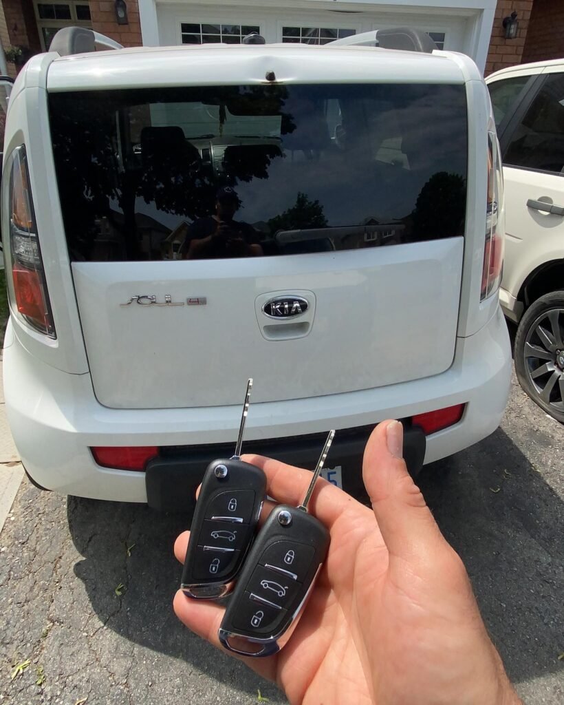 holding a kia key at the back of the car