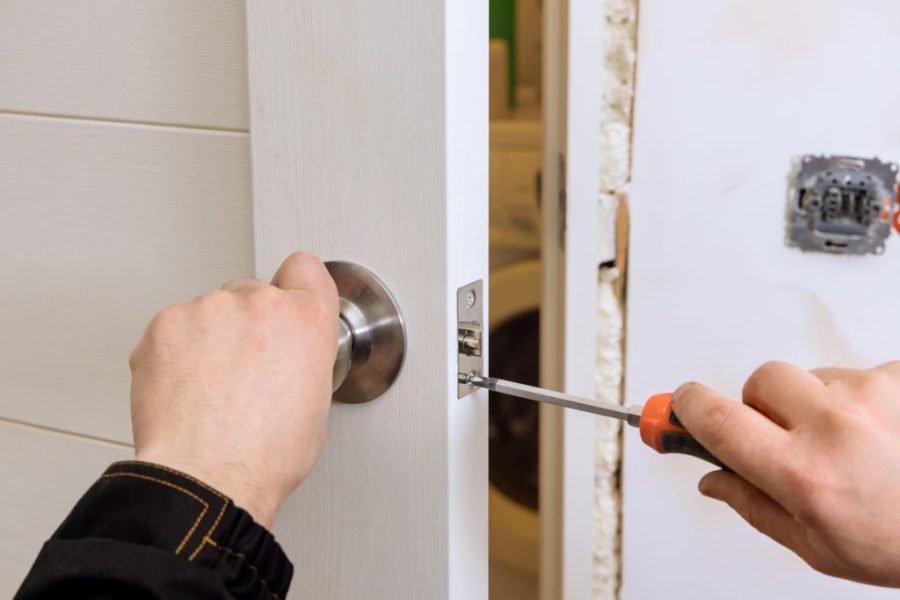 Emergency Locksmith Help for Apartment Lockouts hand holding a screw driver fixing a door knob